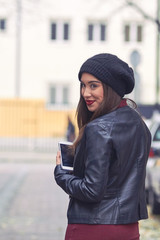 Young woman with hat and cellphone on the street.