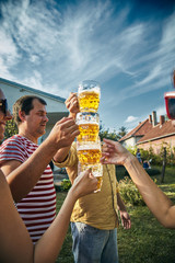 Group of young people enjoying and cheering beer outdoors.