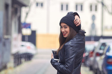Young woman with hat and cellphone on the street.