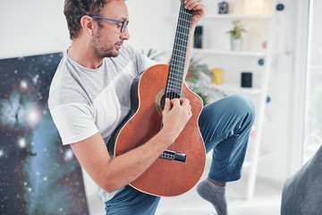 Man playing acoustic guitar in the living room.