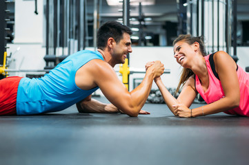 Two athletes doing arm wrestling challenge while lying on floor of gym