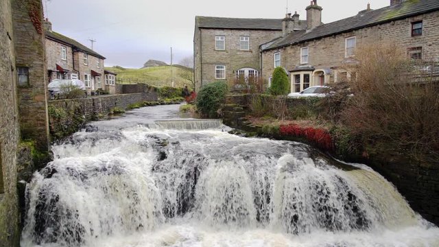 HAWES, YORKSHIRE DALES, ENGLAND, UK - FEBRUARY 19, 2018: Slow motion clip of river Hawes running through the centre of Hawes village in the Yorkshire Dales.
