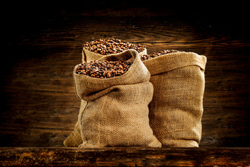 Fresh coffee in sack and wooden wall background 