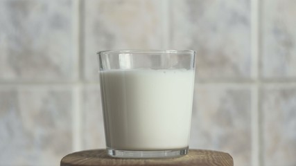 Glass transparent glass. Fresh white milk. Against the background of bright kitchen tiles. Large view.