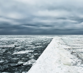 Harsh winter view of the Black Sea coast. Odessa. Huge ice floes and pier in outgrowths of ice and...