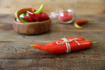 Close-up organic red hot chili peppers on wooden rustic table on the background of an assortment of pepper. Ingredient. Natural spice or seasoning for health. Poster, pattern, background, texture.