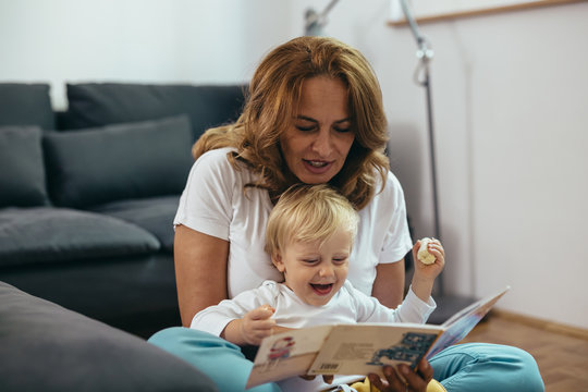 grandmother with her grandson reading picture book together at home