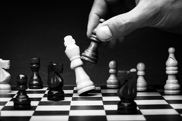Business man playing chess - checkmate. Close-up chess pieces