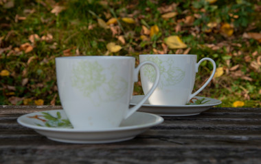 Two cups of tea stand on a wooden surface