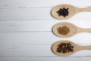 juniper, cumin and peppercorn mix in serving spoons on wooden background. Image contains copy space