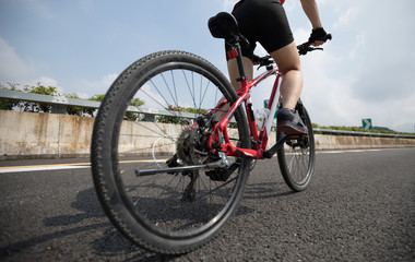 Fototapeta na wymiar Woman cyclist legs riding Mountain Bike on highway