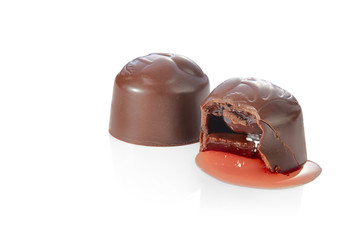 Two lovely chocolates candies with cherries and liqueur, one of which is bitten, isolated on a white background with reflections. Sharpness throughout the frame.