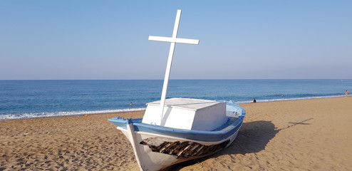 Boot mit Schramme und Kreuz am Meer