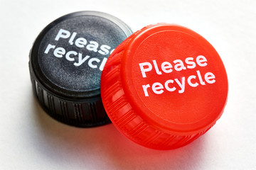 Black and red bottle cap with please recycle message against a white background. Concept of plastic pollution. 