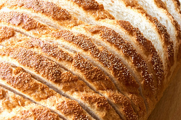 Slices of bread. Extreme closeup of freshly baked white sliced country bread with a crispy crust on wooden cutting board for use as a bakery background.