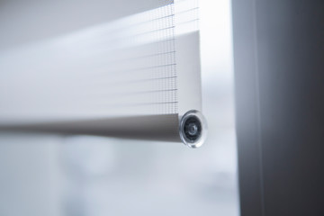 Details of white fabric roller blinds on the white plastic window in the living room. Close up on...