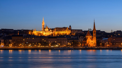 Panoramic view of Szilágyi Dezső Square Reformed Church and Matthias Church on the west bank of the river Danube captured at the blue hour.