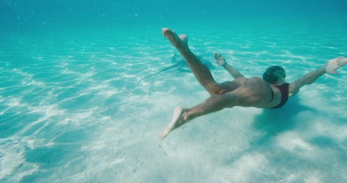 Beautiful woman underwater with stingrays