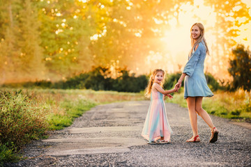Mom and daughter are walking along country road