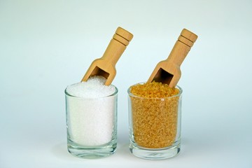 White and brown sugar put separately in glasses with wooden spoons in each glass in the same direction.
