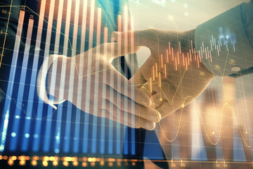 Double exposure of financial graph on cityscape background with two businessman handshake. Concept of stock market deal