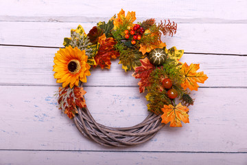 Decorative autumn wreath depicting various crops hanging on a rustic wooden fence.