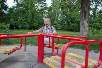 boy spins on a carousel,boy playing on playground, happy boy sitting on carousel