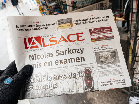 STRASBOURG, FRANCE  - MAR 22, 2018: Man reading buying French L'Alsace  at press kiosk featuring article about legal issues of former French President Nicolas Sarkozy