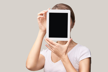 Girl holding computer pad. Mock up at tablet black screen. Face near laptop. Woman showing pc