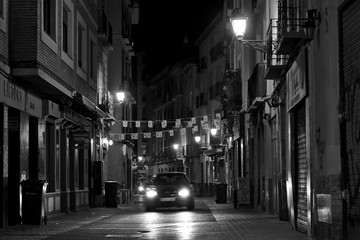 Escena nocturna en blanco y nego de un coche en una calle antigua