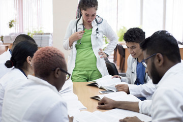 doctors at a medical conference. A group of young people of mixed race, sitting at the table, listening to the lecturer.