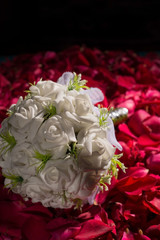 courtesy bouquet of white roses, against the background of red rose petals.