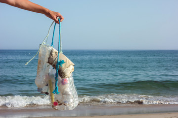 Womanhand picking up trash and plastics cleaning the beach. Environmental volunteer activist...