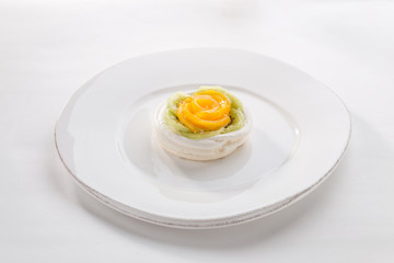 Mini Pavlova meringue nest with peach and kiwi on isolated on white background