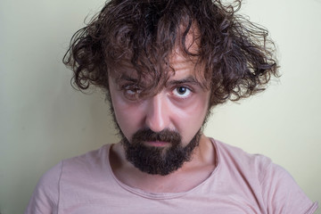 portrait of a young guy with long dirty hair on his head. Looks at the camera.