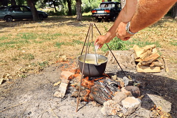 Cooking barbecue and fish soup on a bonfire on a picnic outside the city. Summer, 2019.