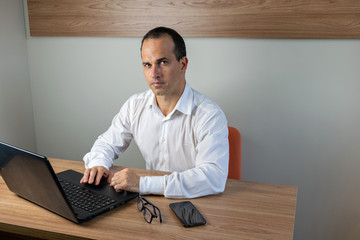 43 year old man working on his notebook and looking at the photo camera.