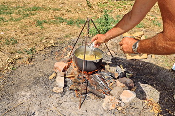 Cooking barbecue and fish soup on a bonfire on a picnic outside the city. Summer, 2019.