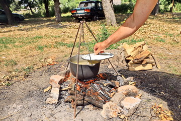 Cooking barbecue and fish soup on a bonfire on a picnic outside the city. Summer, 2019.