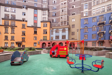Playground for children and house building exterior mixed-use urban multi-family residential district area development at summer evening