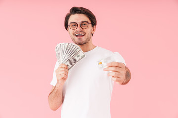 Image of brunette happy man wearing eyeglasses holding cash money and credit card while smiling