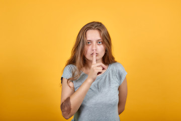 brunette girl in gray t-shirt over isolated orange background shows emotions