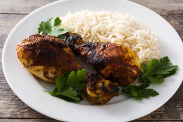 Roasted tandoori chicken with basmati rice in plate on wooden table. 