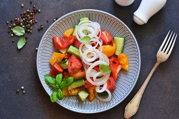 Vegetable vegetarian salad with tomatoes, peppers and onions on the kitchen table. View from above.