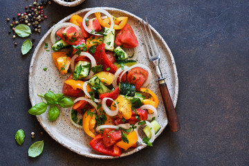 Vegetable vegetarian salad with tomatoes, peppers and onions on the kitchen table. View from above.