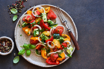 Vegetable vegetarian salad with tomatoes, peppers and onions on the kitchen table. View from above.