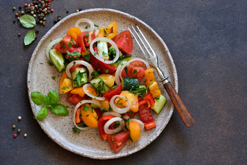 Vegetable vegetarian salad with tomatoes, peppers and onions on the kitchen table. View from above.