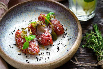 Beef tartare with mushrooms, truffle and capers on a plate. Serving in the restaurant, Haute cuisine