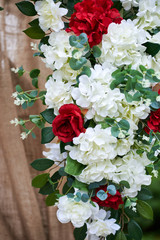 Outdoor wedding decorations, fragment of arch decorated with red and white flowers.