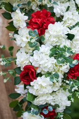 Outdoor wedding decorations, fragment of arch decorated with red and white flowers.